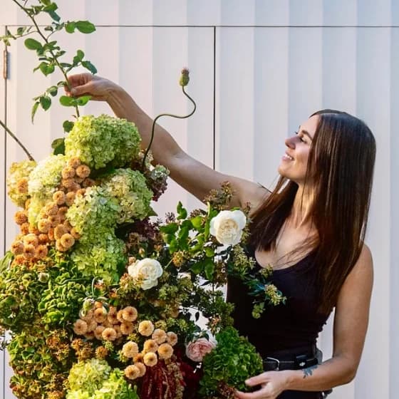 Ashleigh of The Naked Florist, placing stems into a hanging installation