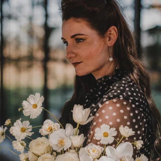 Carmen of Whispering Thorns, holding a bouquet of white cosmos, tulips and roses