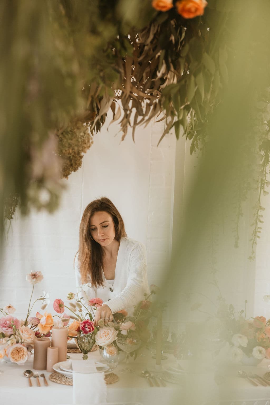 Pippa dressing a table beneath a hanging floral installation