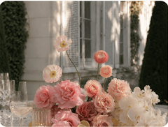Pink garden roses and ranunculus beside glassware